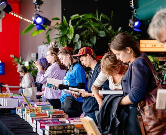 Mensen bekijken boeken tijdens de boekenmarkt Exploring Stories op een eerdere editie van ILFU