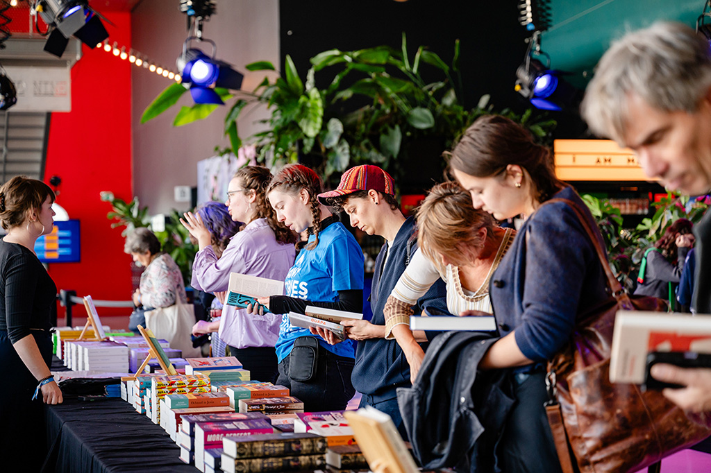 Mensen bekijken boeken tijdens de boekenmarkt Exploring Stories op een eerdere editie van ILFU