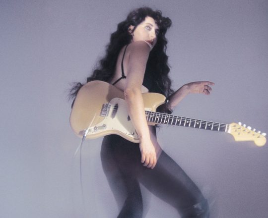 Eefje de Visser, poseert met haar gitaar. De foto wordt gebruikt als headerfoto in het online artikel en staat op de cover van het magazine van februari 2026.